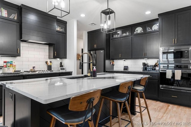 21933 E 101st Pl S, Broken Arrow, OK 74014 - kitchen with stainless steel appliances, backsplash, exhaust hood, light stone counters, and recessed lighting