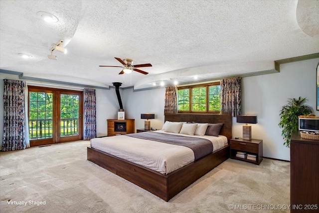 1943 W 163rd St, Skiatook, OK 74070 - carpeted bedroom featuring a textured ceiling, a wood stove, access to exterior, ornamental molding, and a ceiling fan