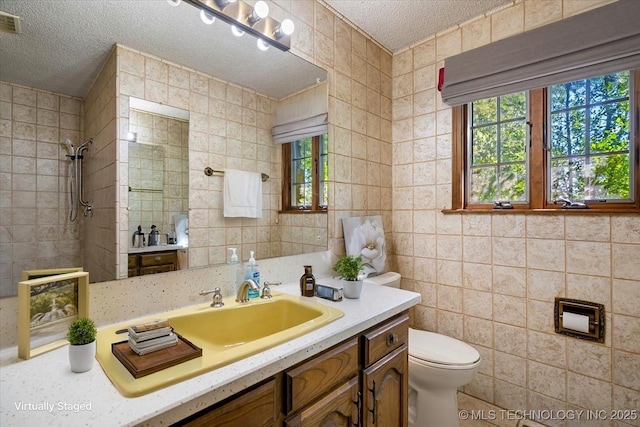 1943 W 163rd St, Skiatook, OK 74070 - bathroom with tile walls, a textured ceiling, vanity, and a tile shower