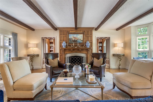 1249 E 26th St, Tulsa, OK 74114 - living area with a textured ceiling, beamed ceiling, wood finished floors, a textured wall, and a fireplace