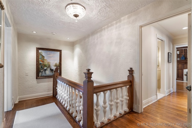 1249 E 26th St, Tulsa, OK 74114 - hallway with a textured wall, wood finished floors, a textured ceiling, ornamental molding, and an upstairs landing