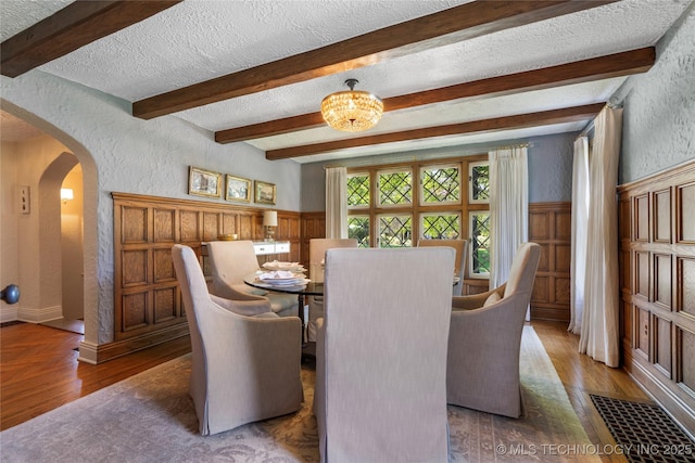 1249 E 26th St, Tulsa, OK 74114 - dining area with a textured wall, a textured ceiling, arched walkways, wainscoting, and beam ceiling