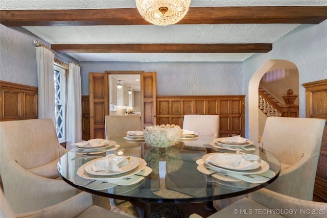 1249 E 26th St, Tulsa, OK 74114 - dining area featuring a textured wall, beamed ceiling, arched walkways, and stairs
