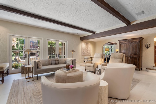 1249 E 26th St, Tulsa, OK 74114 - living room featuring a textured wall, a textured ceiling, arched walkways, beam ceiling, and healthy amount of natural light