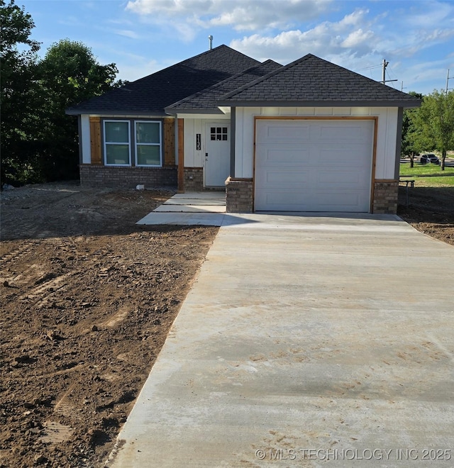1135 E Zion St, Tulsa, OK 74106 - view of front of property featuring driveway, brick siding, a garage, roof with shingles, and board and batten siding