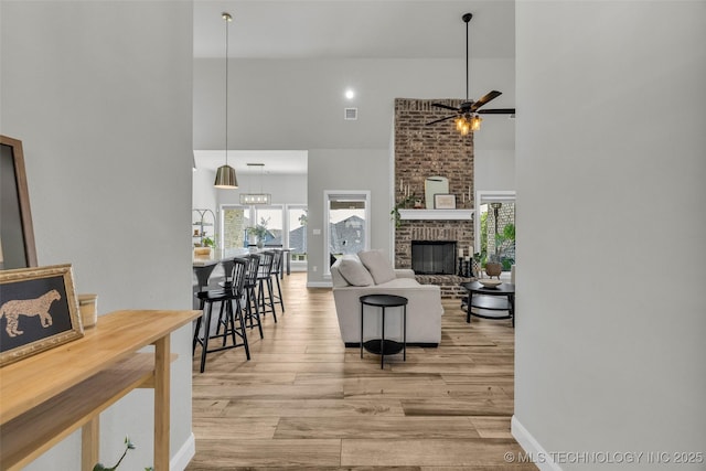 25133 Shade Tree Pl, Claremore, OK 74019 - living room featuring a towering ceiling, a ceiling fan, light wood finished floors, and plenty of natural light
