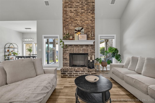 25133 Shade Tree Pl, Claremore, OK 74019 - living area featuring wood finished floors, a brick fireplace, and a chandelier
