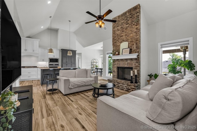 25133 Shade Tree Pl, Claremore, OK 74019 - living room with light wood finished floors, high vaulted ceiling, a ceiling fan, and a brick fireplace