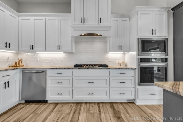 25133 Shade Tree Pl, Claremore, OK 74019 - kitchen featuring stainless steel appliances, white cabinets, light wood-style flooring, and tasteful backsplash