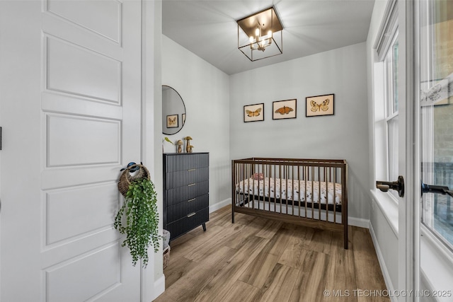 25133 Shade Tree Pl, Claremore, OK 74019 - bedroom featuring wood finished floors, a nursery area, a chandelier, and multiple windows