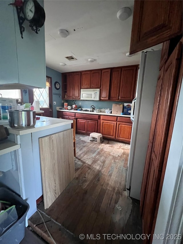 13226 N 91st Ave E, Collinsville, OK 74021 - kitchen featuring white appliances, wood-type flooring, light countertops, and a peninsula