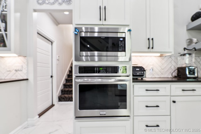 7604 S 6th St, Broken Arrow, OK 74011 - kitchen featuring stainless steel appliances, light marble finish flooring, decorative backsplash, dark countertops, and white cabinetry