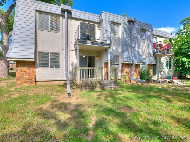4654 E 68th St S Unit 199, Tulsa, OK 74136 - rear view of property featuring a balcony, stone siding, and a lawn
