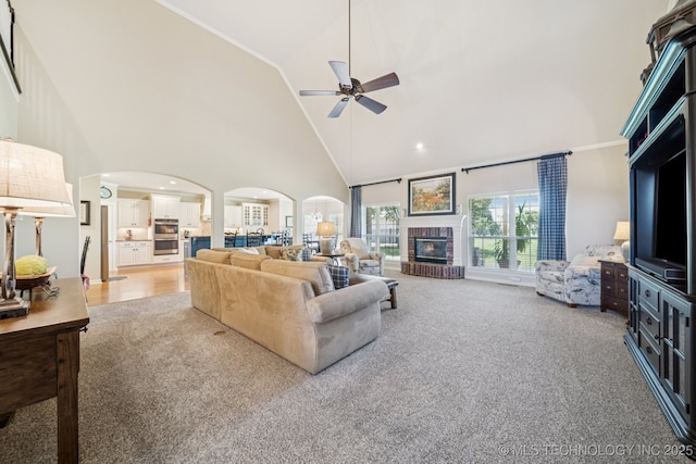 13614 W 42nd Pl, Sand Springs, OK 74063 - living room with arched walkways, high vaulted ceiling, ceiling fan, light colored carpet, and a brick fireplace