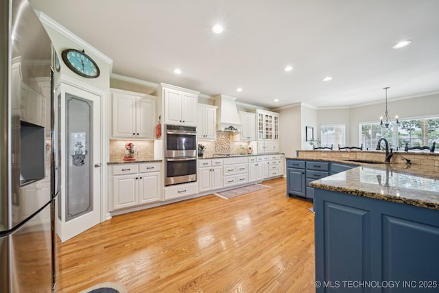 13614 W 42nd Pl, Sand Springs, OK 74063 - kitchen featuring stainless steel appliances, premium range hood, white cabinets, crown molding, and light wood-type flooring