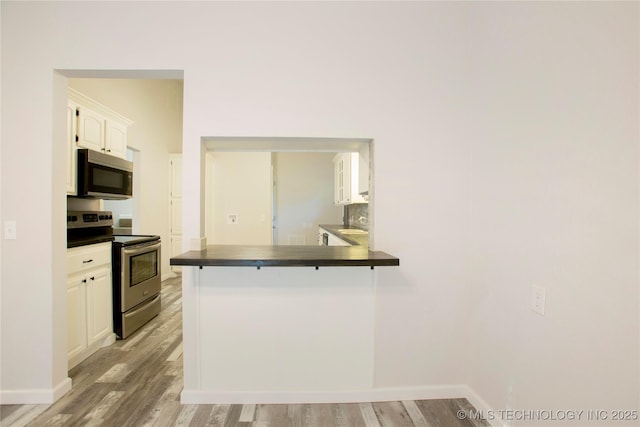 416434 Lakeside, Checotah, OK 74426 - kitchen with stainless steel appliances, dark countertops, white cabinetry, and light wood finished floors