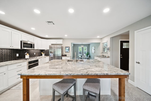 7705 S 232nd E Ave, Broken Arrow, OK 74014 - kitchen featuring appliances with stainless steel finishes, a kitchen bar, recessed lighting, white cabinets, and light stone countertops