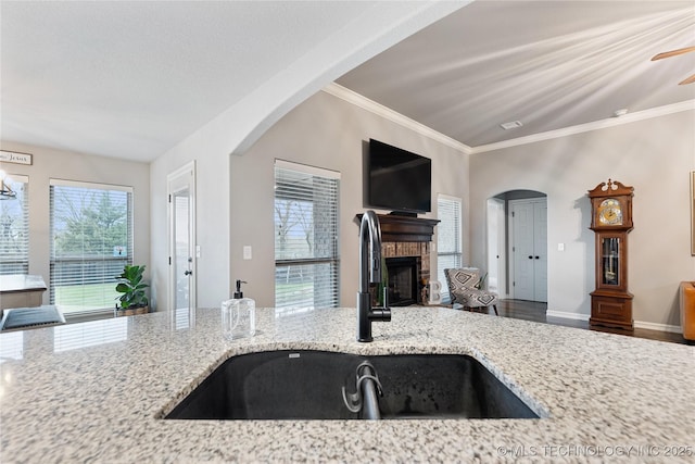 1819 E 43rd St, Sand Springs, OK 74063 - kitchen featuring open floor plan, light stone counters, a brick fireplace, a ceiling fan, and ornamental molding