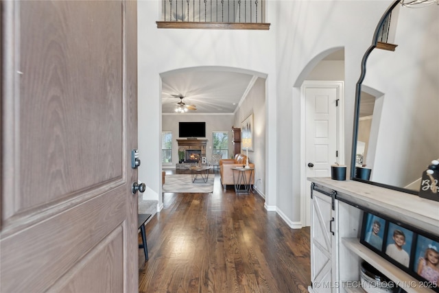 1819 E 43rd St, Sand Springs, OK 74063 - entrance foyer with a fireplace, ornamental molding, ceiling fan, dark wood-type flooring, and arched walkways