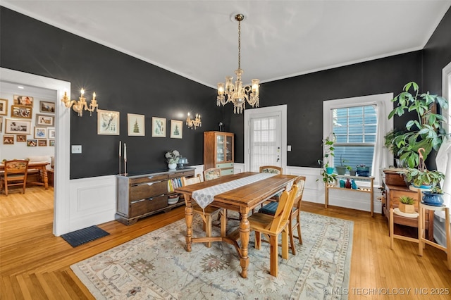 1006 E 17th Pl, Tulsa, OK 74120 - dining room featuring a chandelier, wainscoting, crown molding, light wood finished floors, and a decorative wall