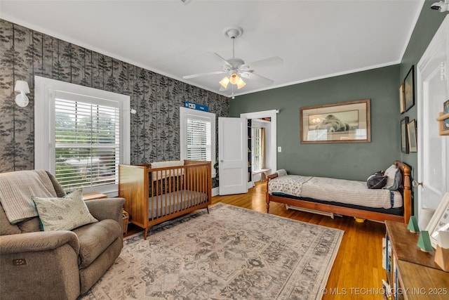 1006 E 17th Pl, Tulsa, OK 74120 - bedroom featuring wallpapered walls, wood finished floors, ornamental molding, and a ceiling fan