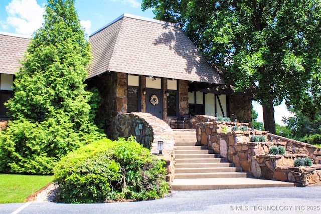 56701 E 310th Rd Unit 712, Afton, OK 74331 - view of front of property featuring stone siding, a shingled roof, stairway, and a porch