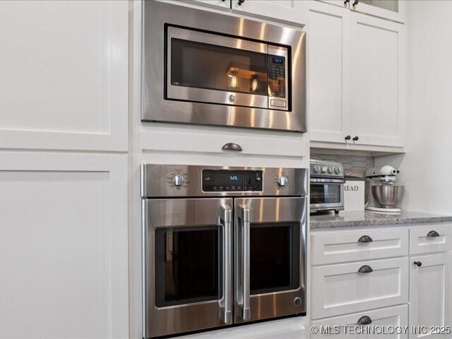 4270 S 4110th Rd, Talala, OK 74080 - kitchen featuring appliances with stainless steel finishes, white cabinets, light stone counters, and tasteful backsplash