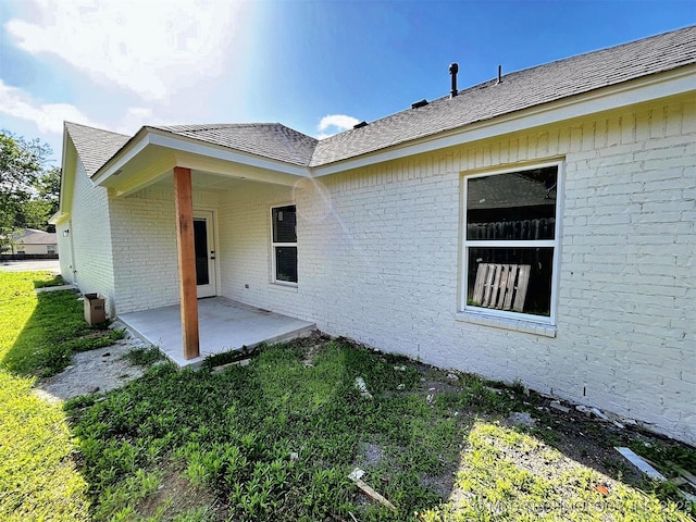 2005 N Alora Ave, Tahlequah, OK 74464 - doorway to property featuring brick siding, a patio, and a shingled roof