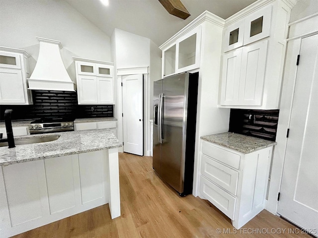 2005 N Alora Ave, Tahlequah, OK 74464 - kitchen with stainless steel appliances, custom exhaust hood, white cabinetry, decorative backsplash, and light wood finished floors