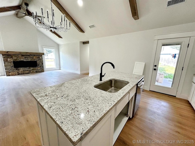 2005 N Alora Ave, Tahlequah, OK 74464 - kitchen featuring light wood finished floors, dishwasher, a center island with sink, light stone countertops, and a stone fireplace