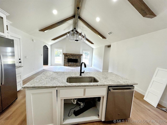 2005 N Alora Ave, Tahlequah, OK 74464 - kitchen with stainless steel appliances, open floor plan, light wood-style flooring, a center island with sink, and arched walkways