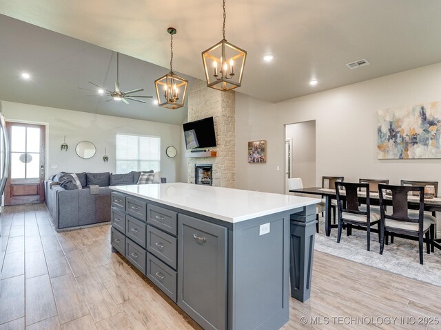 12349 County Road 3571, Ada, OK 74820 - kitchen with a chandelier, a ceiling fan, gray cabinetry, a fireplace, and light countertops
