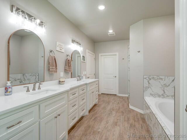 12349 County Road 3571, Ada, OK 74820 - bathroom with double vanity, a garden tub, wood finished floors, and recessed lighting
