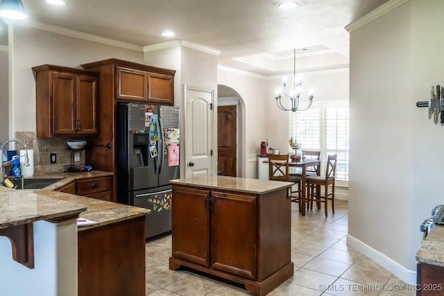 12901 N 124th E Pl, Collinsville, OK 74021 - kitchen with black fridge with ice dispenser, arched walkways, light stone counters, a chandelier, and tasteful backsplash