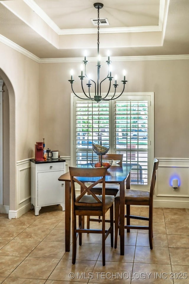 12901 N 124th E Pl, Collinsville, OK 74021 - dining space with a tray ceiling, arched walkways, a chandelier, light tile patterned floors, and crown molding