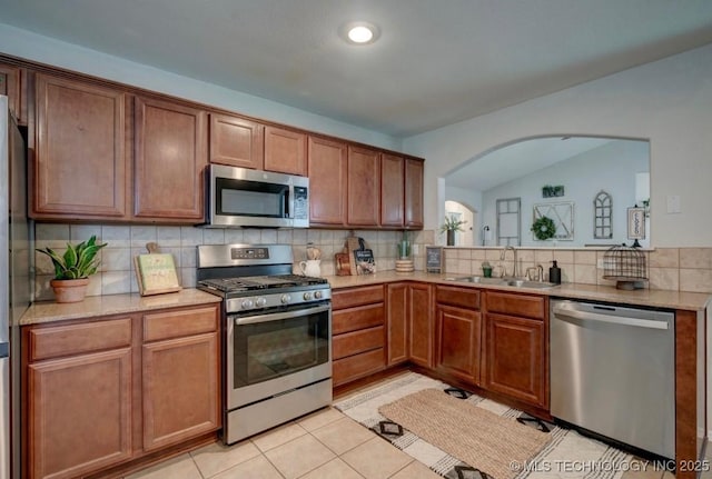 11001 N 146th E Ave, Owasso, OK 74055 - kitchen with appliances with stainless steel finishes, arched walkways, tasteful backsplash, brown cabinetry, and light tile patterned flooring