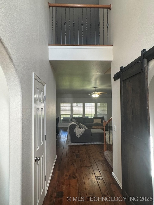 11725 S Vine Pl S, Jenks, OK 74037 - hall featuring hardwood / wood-style flooring, a high ceiling, arched walkways, and a barn door