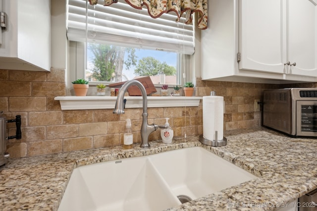 2807 W Atlanta Pl, Broken Arrow, OK 74012 - kitchen view of white cabinetry, backsplash, and light stone counters