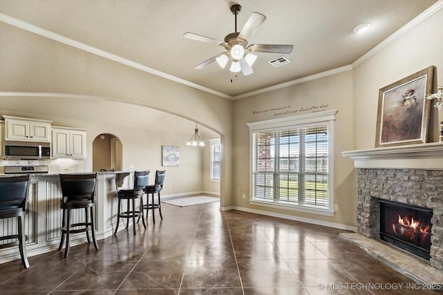 1854 E 137th Pl, Glenpool, OK 74033 - kitchen with stainless steel microwave, arched walkways, a breakfast bar, ceiling fan, and a fireplace