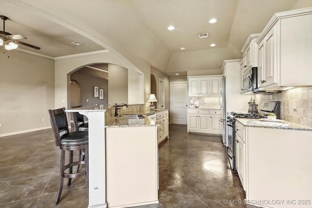 1854 E 137th Pl, Glenpool, OK 74033 - kitchen with stainless steel appliances, a ceiling fan, a breakfast bar area, arched walkways, and recessed lighting