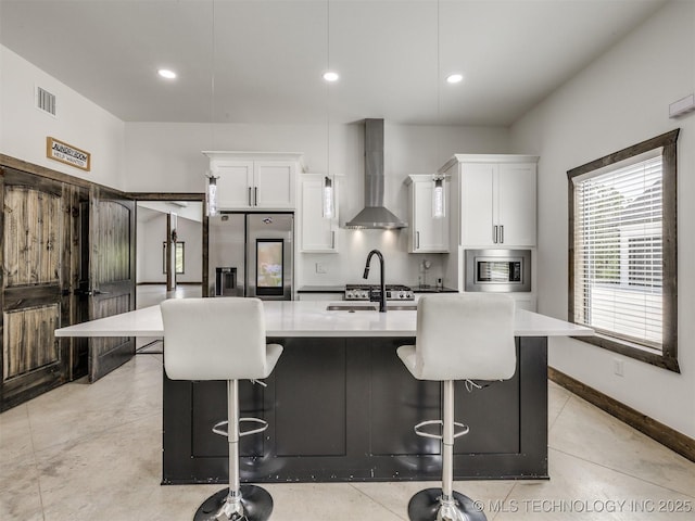 11446 Mary Knox Dr, Beggs, OK 74421 - kitchen with wall chimney range hood, appliances with stainless steel finishes, a kitchen island with sink, white cabinets, and a breakfast bar