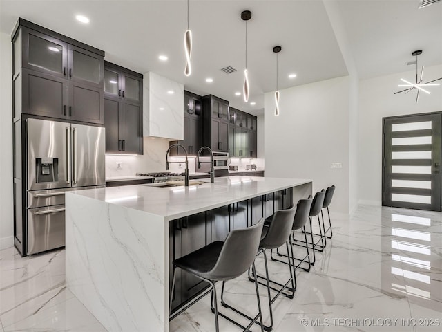 11446 Mary Knox Dr, Beggs, OK 74421 - kitchen featuring appliances with stainless steel finishes, light marble finish flooring, light stone counters, a large island with sink, and recessed lighting