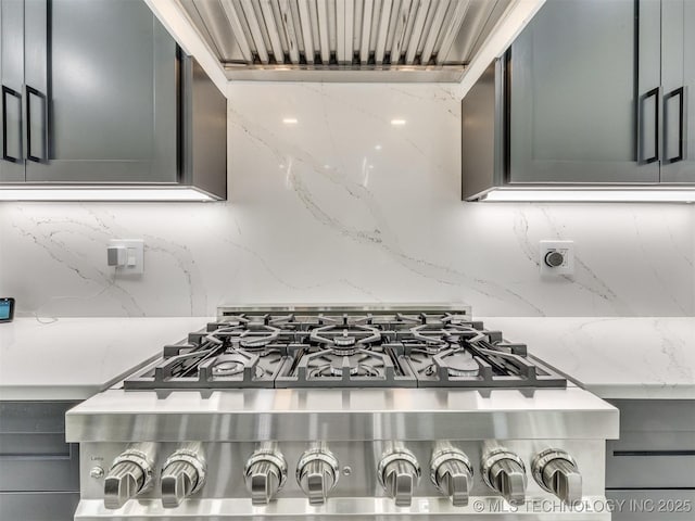 11446 Mary Knox Dr, Beggs, OK 74421 - kitchen view of range hood, tasteful backsplash, light stone counters, and stove