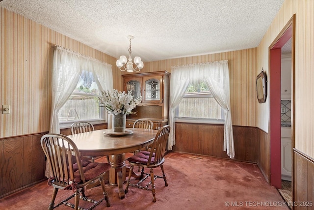 12452 E 36th St, Tulsa, OK 74146 - dining room with healthy amount of natural light, a chandelier, wood walls, a textured ceiling, and carpet flooring