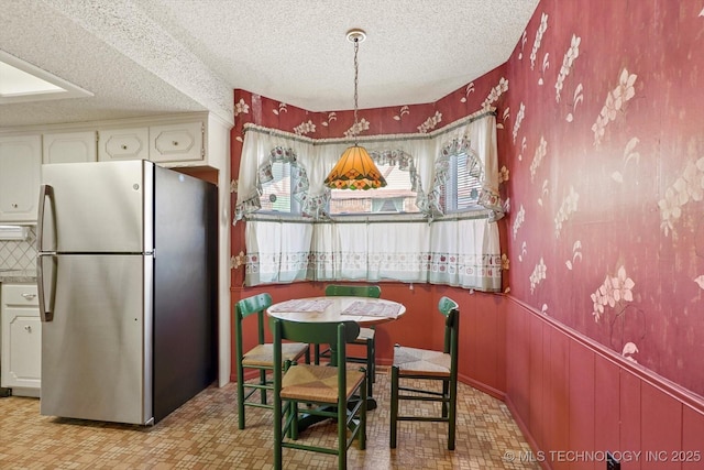 12452 E 36th St, Tulsa, OK 74146 - dining space featuring a textured ceiling, light flooring, and wainscoting