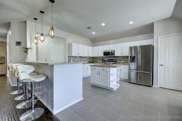124 W 125th Ct S, Jenks, OK 74037 - kitchen featuring appliances with stainless steel finishes, vaulted ceiling, decorative backsplash, light stone countertops, and white cabinetry