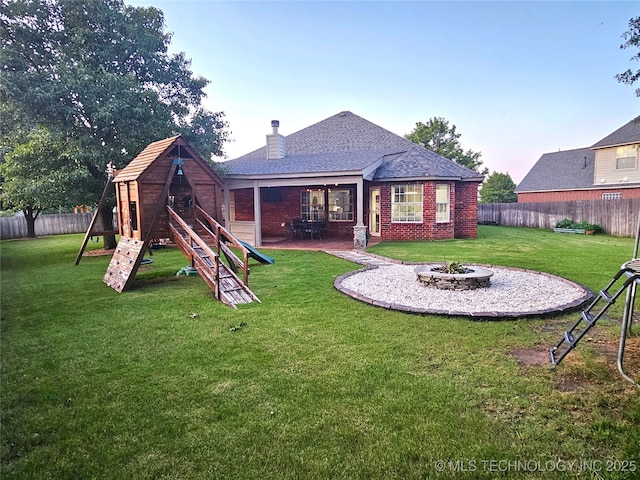 124 W 125th Ct S, Jenks, OK 74037 - back of house at dusk with a playground, a fire pit, brick siding, and a fenced backyard
