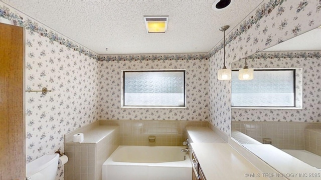 1124 Surrey Dr, Ardmore, OK 73401 - bathroom featuring wallpapered walls, a garden tub, a textured ceiling, tile walls, and vanity