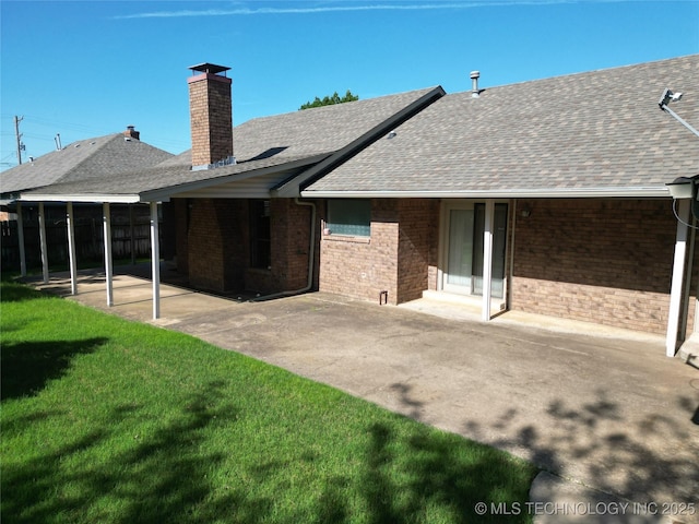 1124 Surrey Dr, Ardmore, OK 73401 - rear view of house featuring roof with shingles, a patio, brick siding, a lawn, and a chimney