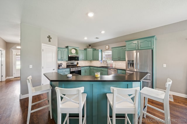 921 S 75th St, Broken Arrow, OK 74014 - kitchen featuring stainless steel appliances, green cabinets, dark wood-style flooring, tasteful backsplash, and dark countertops